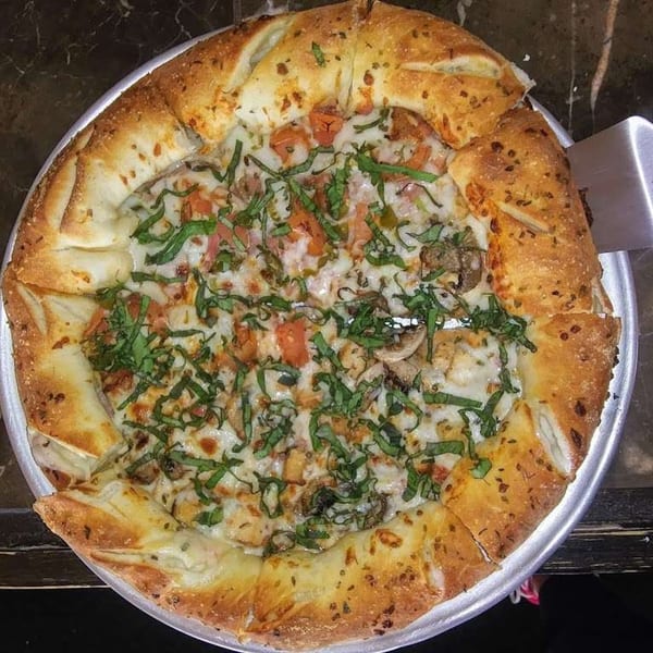 Soprano's Pizza and Pasta's pizza with a garlic knot crust, topped with cheese, tomatoes, and basil.