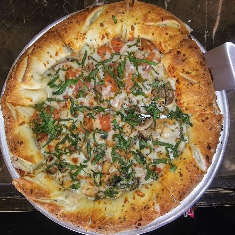 Soprano's Pizza and Pasta's pizza with a garlic knot crust, topped with cheese, tomatoes, and basil.